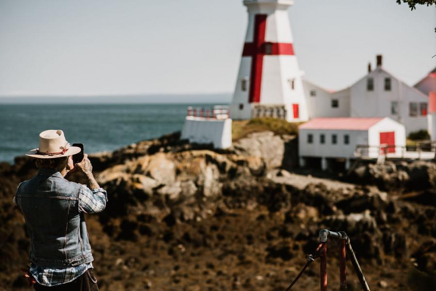 a man taking a picture of the head harbour lighthouse in campobello