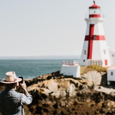 a man taking a picture of the head harbour lighthouse in campobello