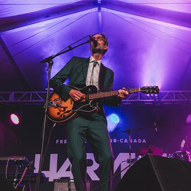 A person singing on stage while also playing guitar.