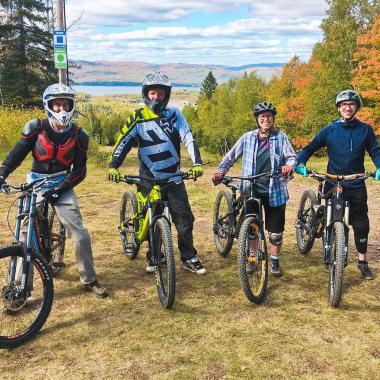 Four people posing for a photo while sitting on their bicycles.
