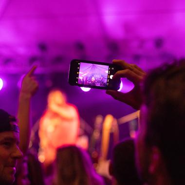 A person recording a musical performance on their phone during Harvest Music Festival