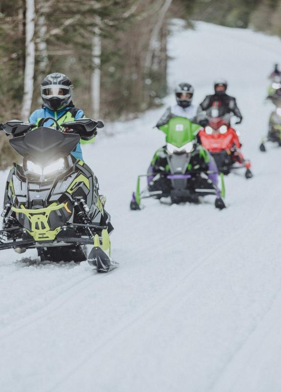 people snowmobiling on a trail in new brunswick