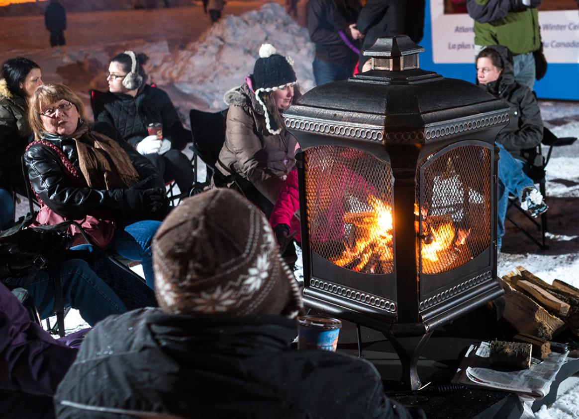 People sitting around a wood stove during the Frostival.