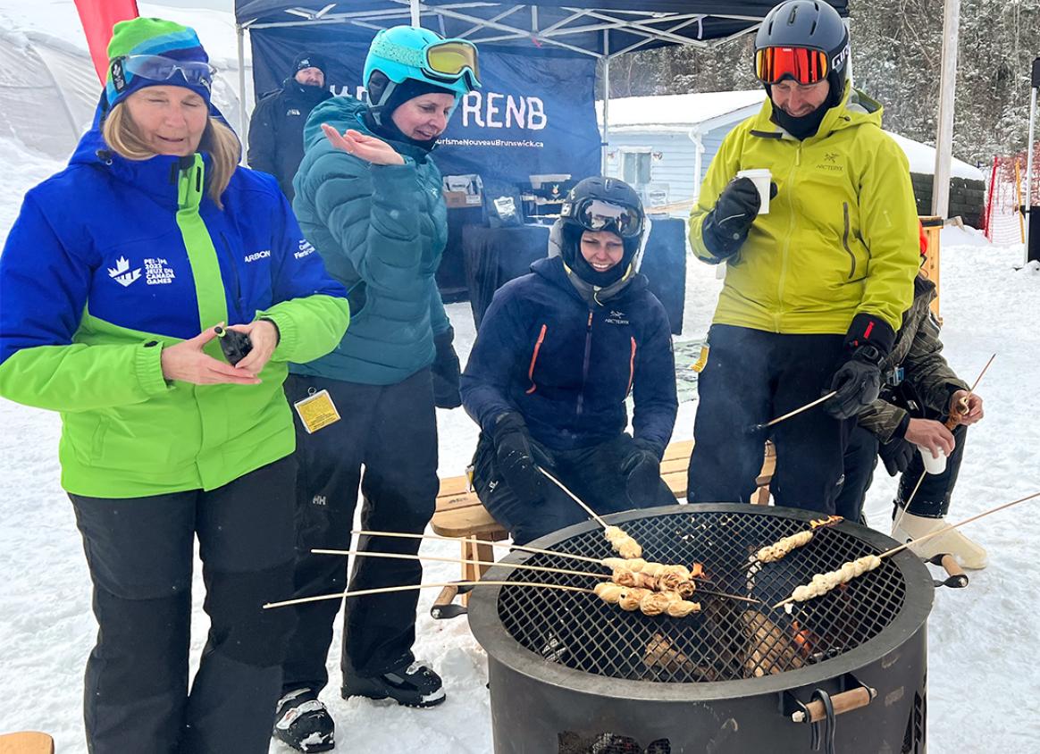 Snowboarders roasting food on skewers on Crabbe Mountain.